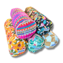 A collection of colorful Tiny Yoga bolster pillows with various patterns.