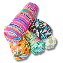 A collection of colorful Tiny Yoga bolster pillows with various patterns.